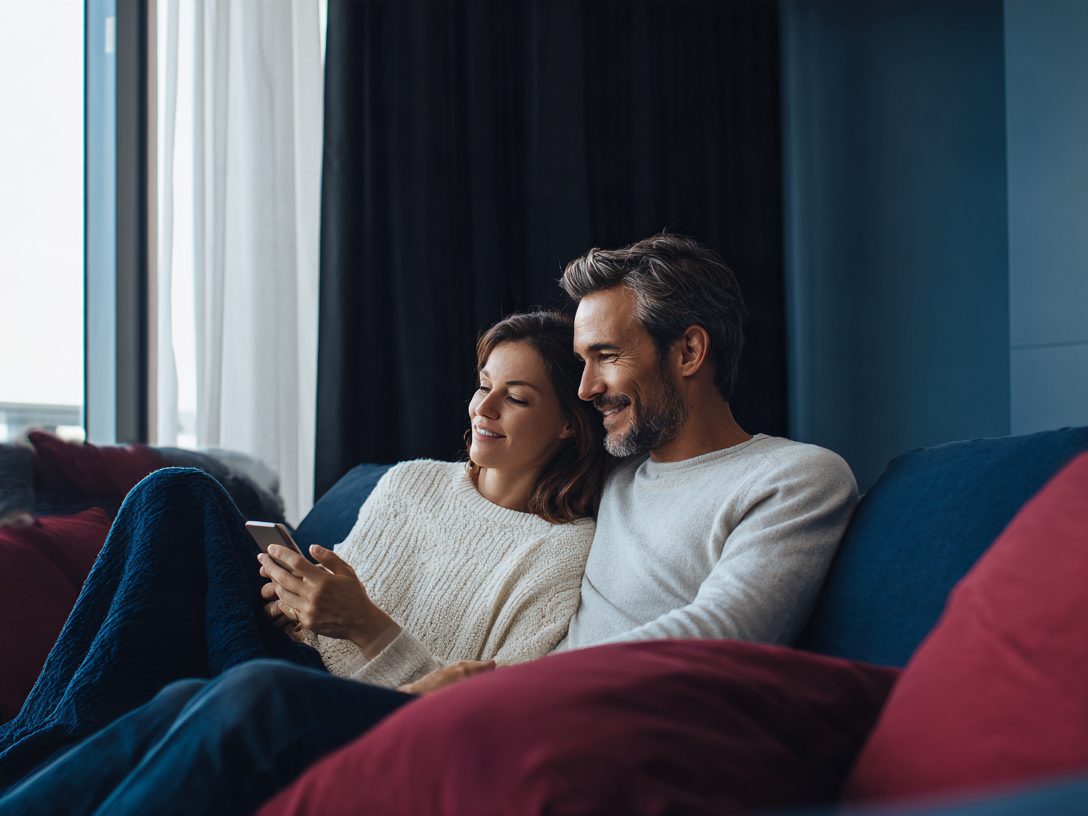 Pareja adulta mirando un celular en el living de su casa
